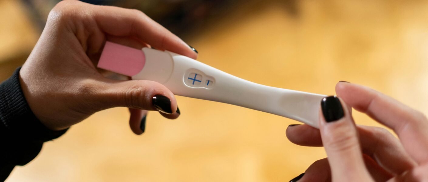 Closeup of hands holding a positive pregnancy test with a cross symbol.