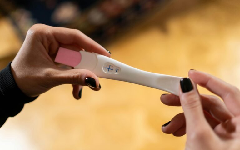 Closeup of hands holding a positive pregnancy test with a cross symbol.