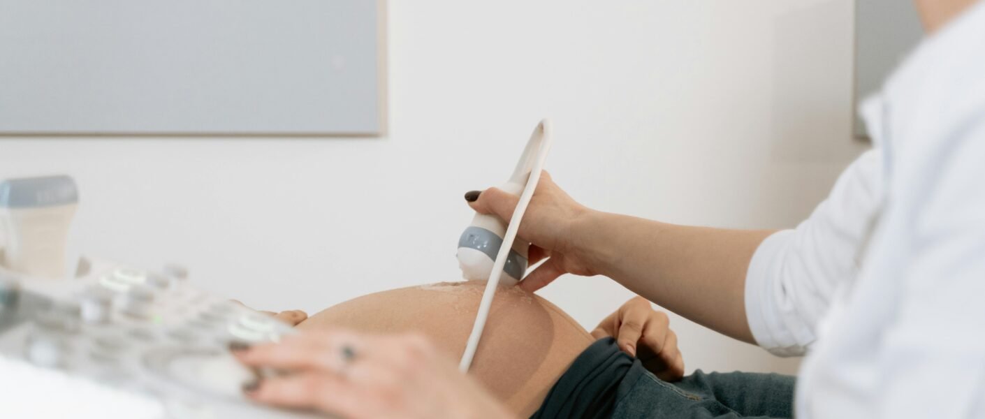 A healthcare professional performs an ultrasound on a pregnant woman in a clinic.